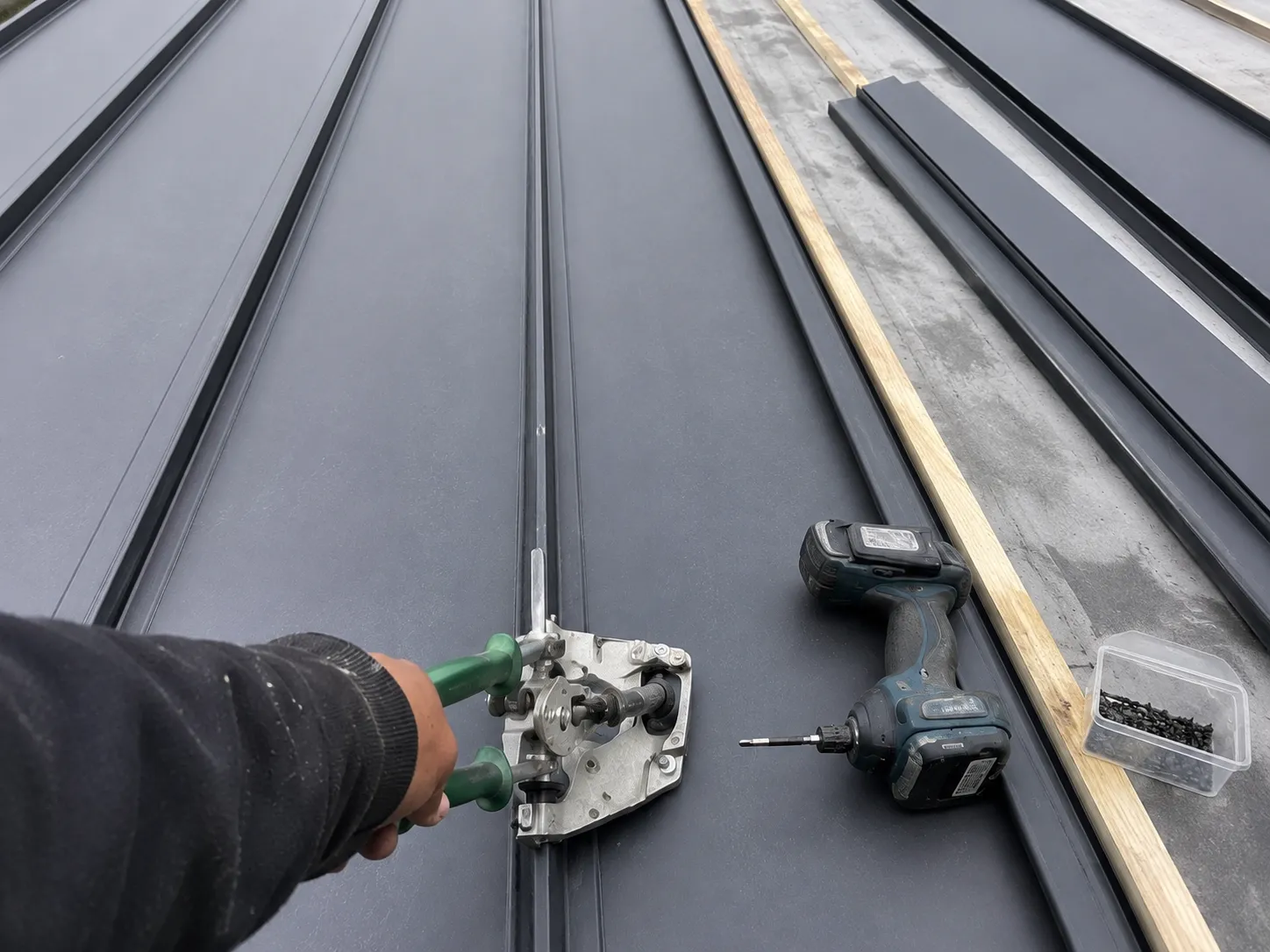 Roofer's-eye view of fastening a standing seam during installation