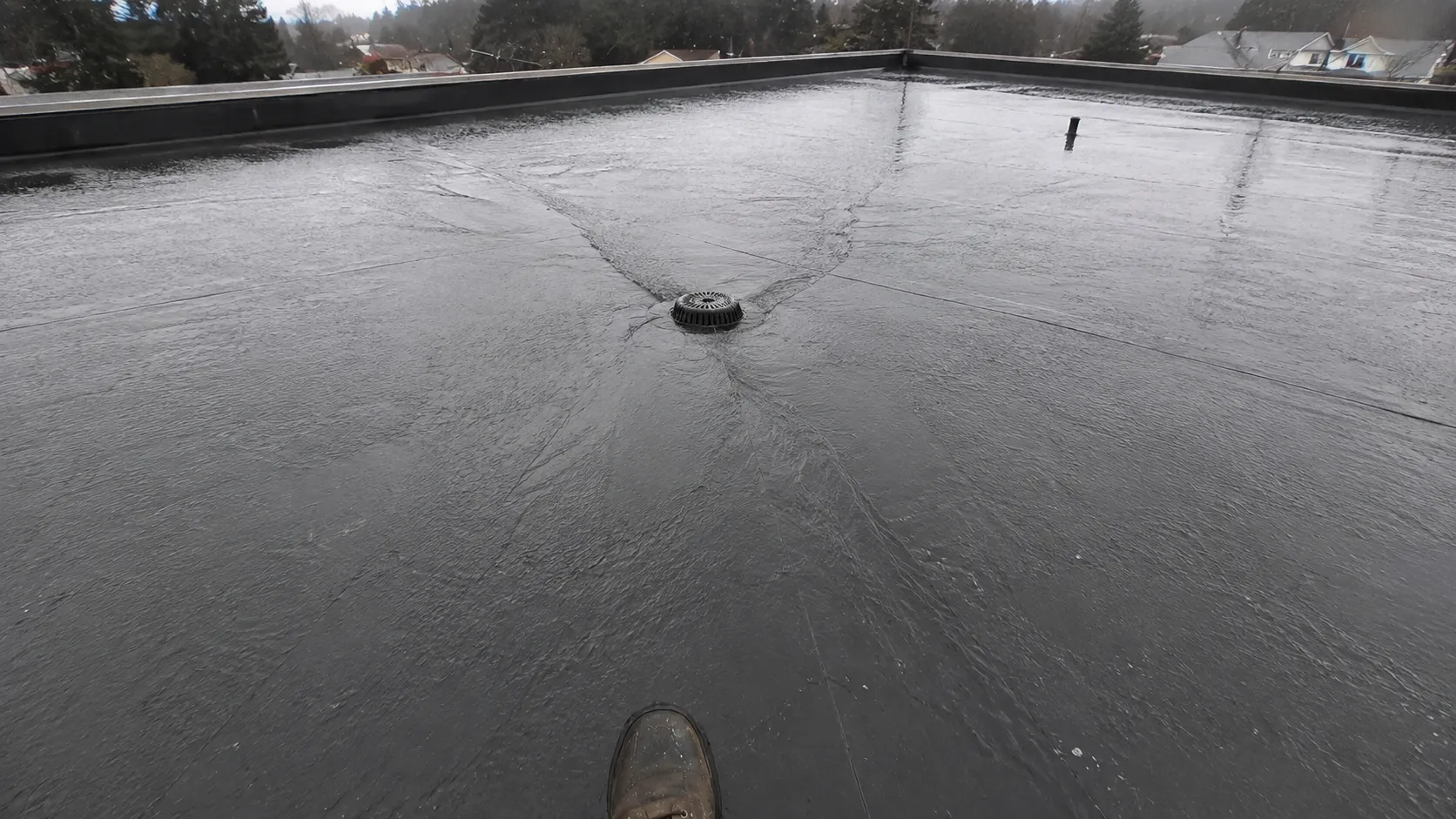 Flat roof drainage inspection showing rainwater flowing to the drain — Surrey, BC